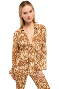 Woman wearing a brown and beige patterned outfit on a plain background