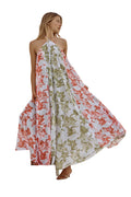 Woman wearing a floral one-shoulder dress against a white wall.
