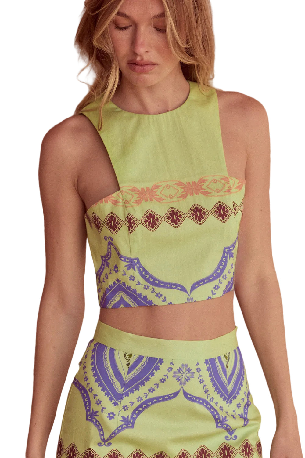 Woman wearing a green sleeveless top with patterned design on a white background