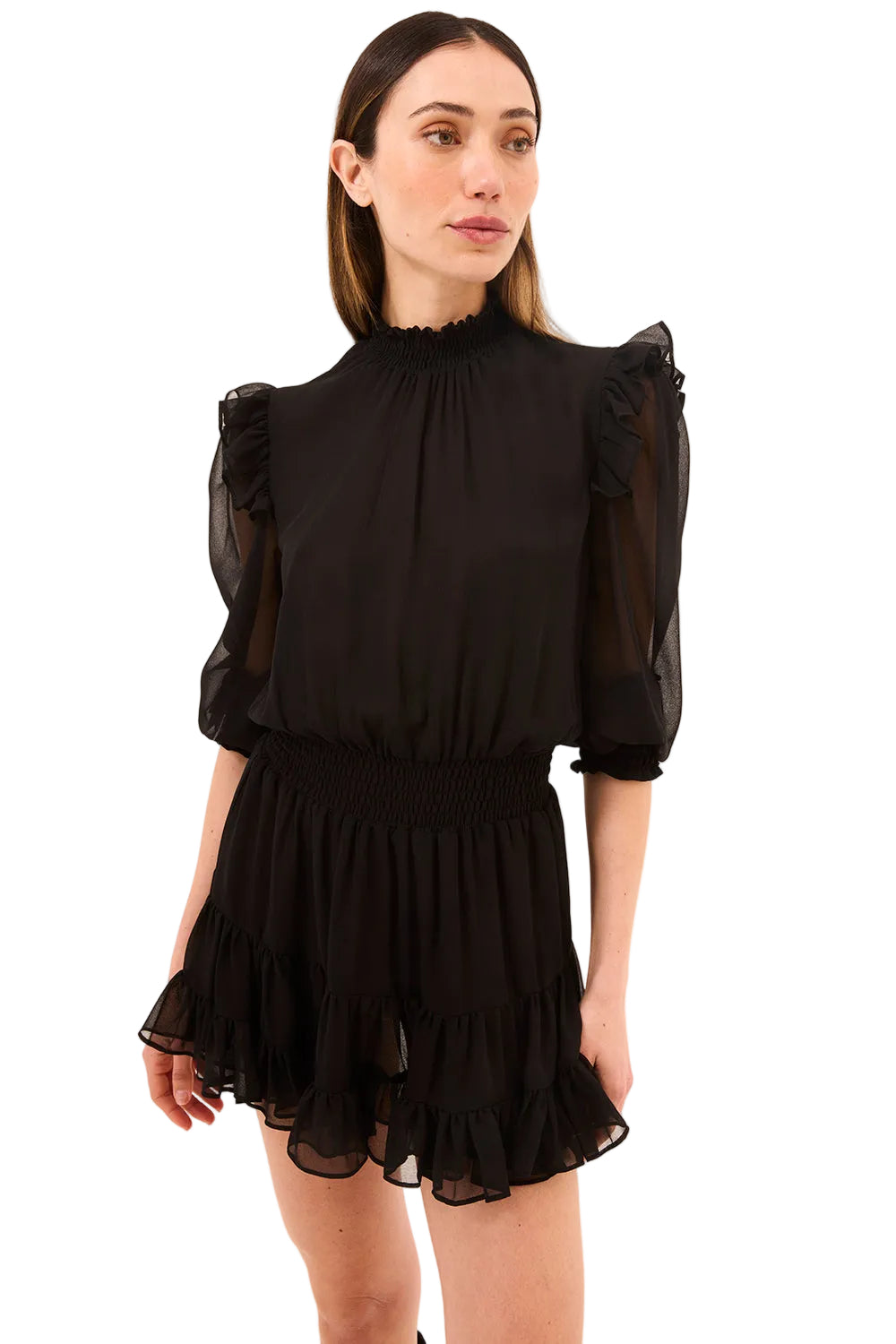 Woman wearing a black dress with sheer sleeves against a beige background