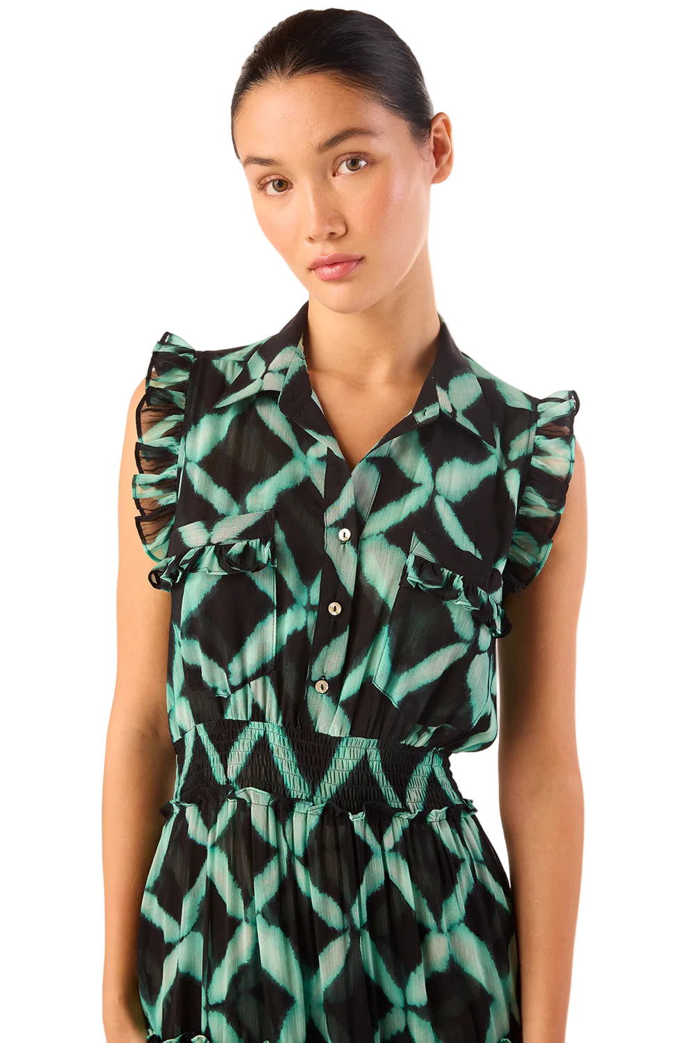 Woman wearing a green and black patterned dress with ruffled shoulders on a white background