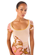 Model wearing a floral dress with pink and gold design on a white background