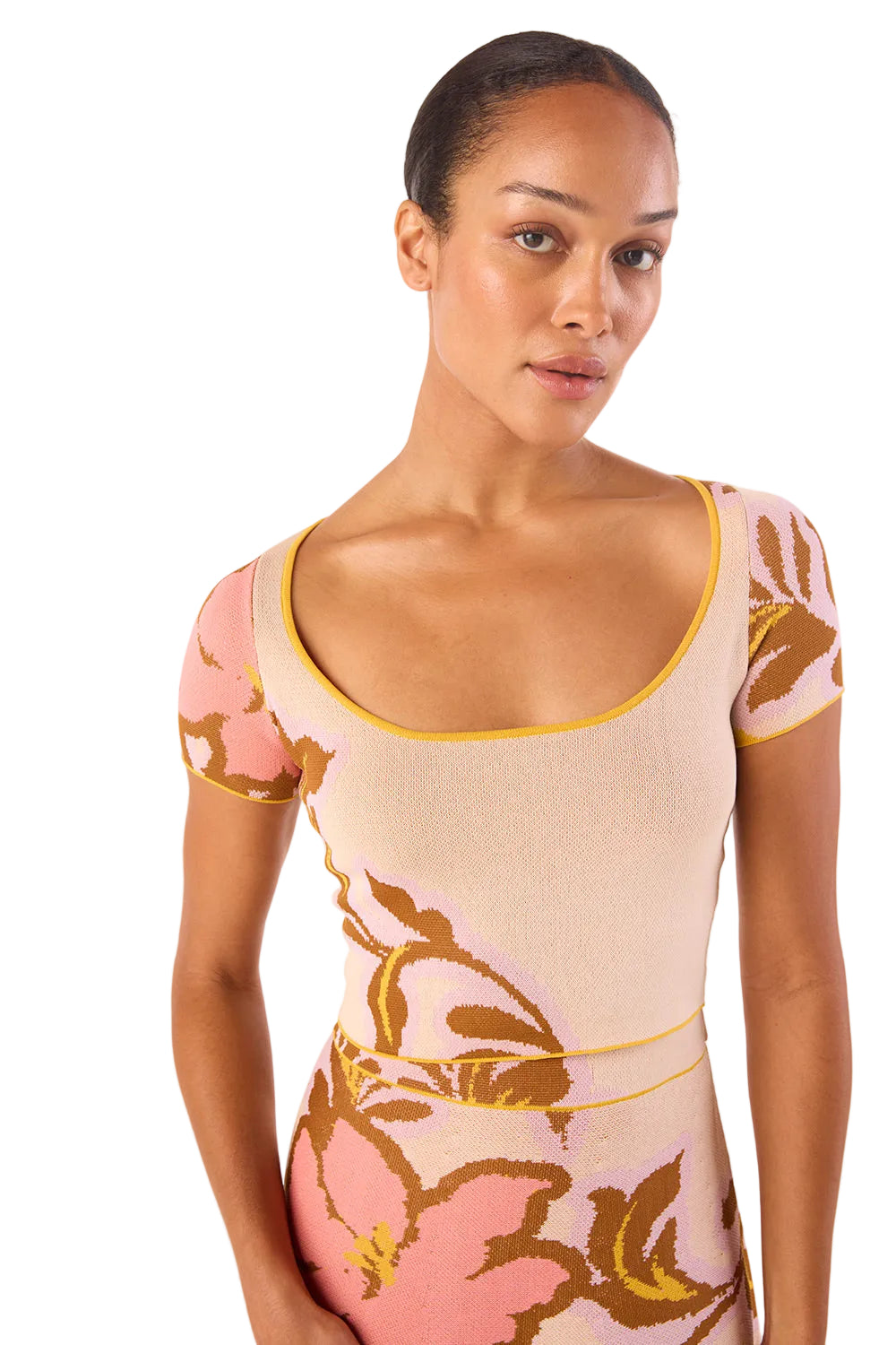 Model wearing a floral dress with pink and gold design on a white background